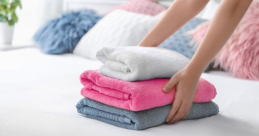 woman holds terry cloth towels standing on the bed